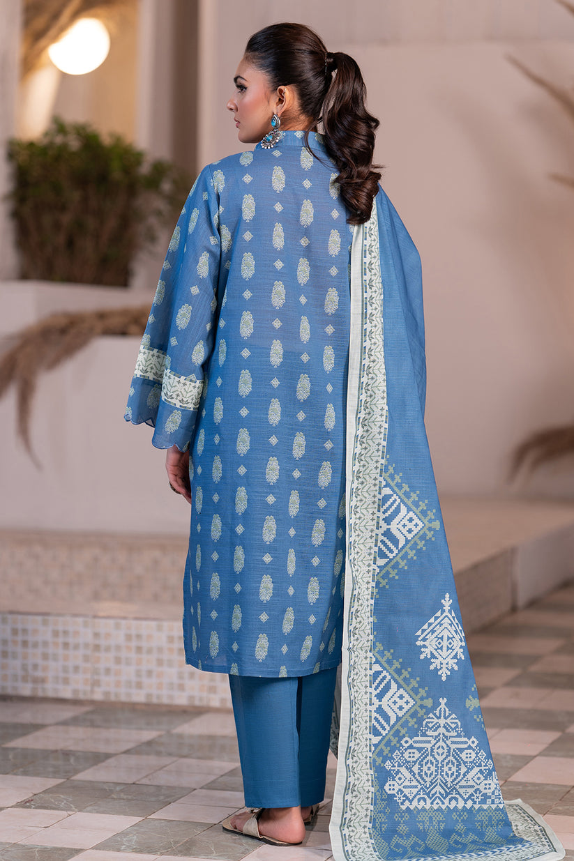 Woman wearing a blue traditional outfit with white patterns in an indoor setting.