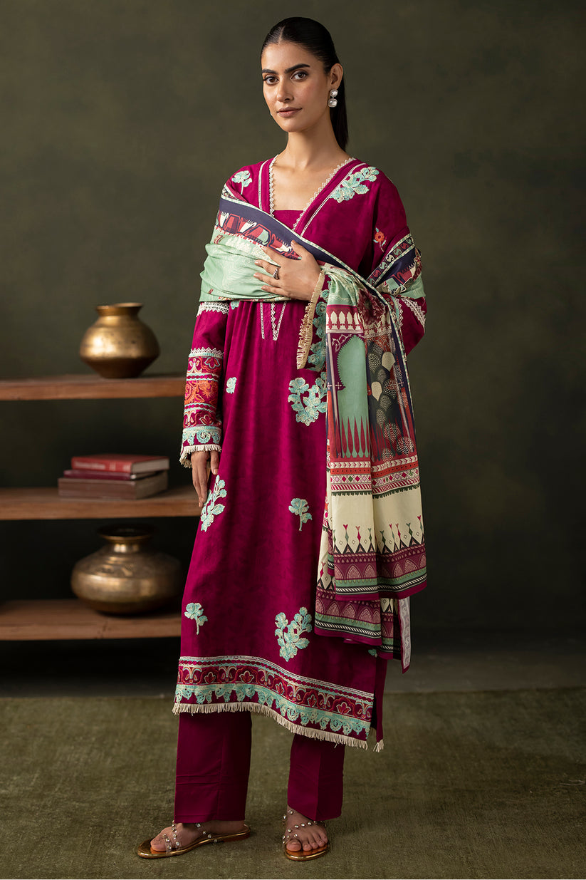Woman wearing a traditional outfit with a patterned shawl against a dark background