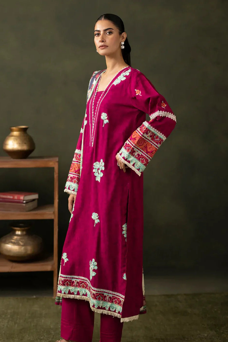 Woman wearing a magenta embroidered traditional outfit with a dark background