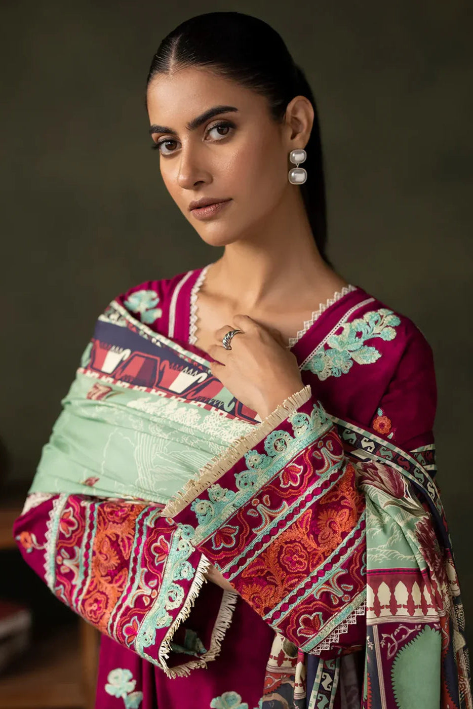 Woman wearing a colorful dress with intricate patterns against a dark background