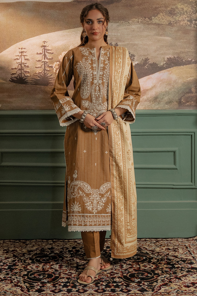 Woman wearing a traditional embroidered outfit standing in front of a decorative wall.