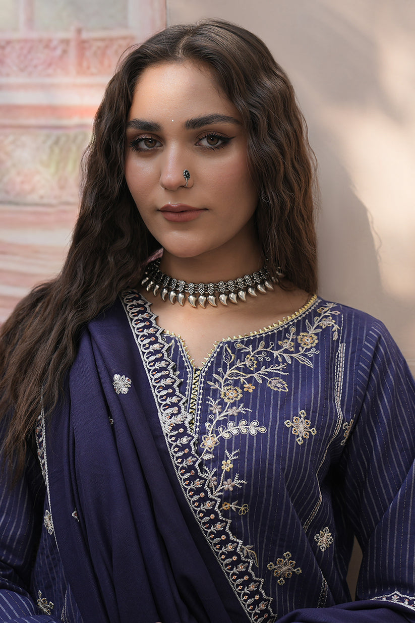 Woman wearing a traditional embroidered outfit with a decorative necklace.