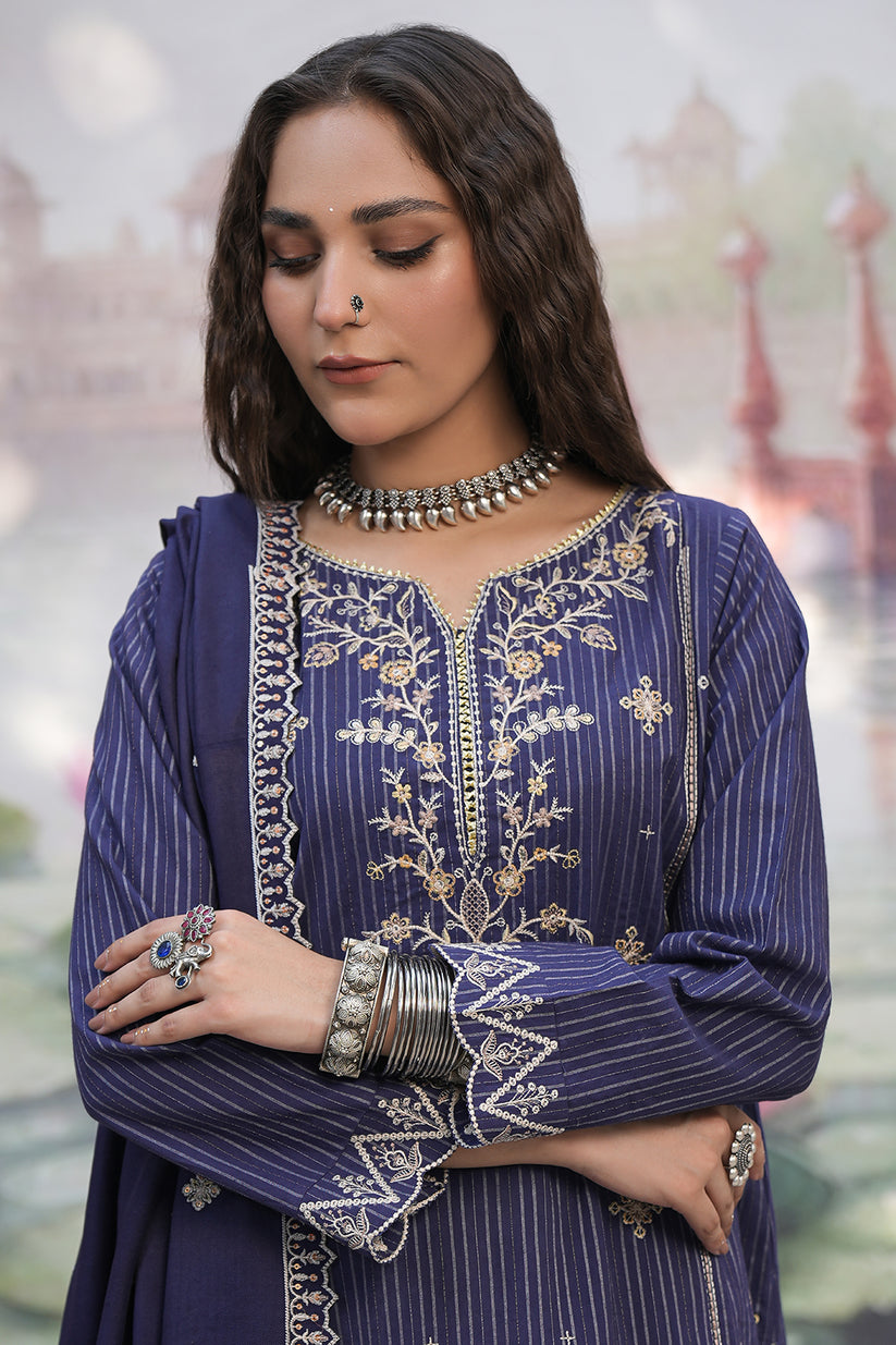 Woman wearing a traditional embroidered purple outfit with jewelry against a blurred background