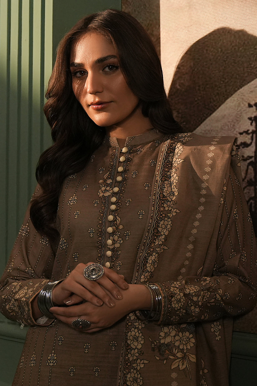 Woman wearing a brown embroidered traditional outfit with a decorative ring.