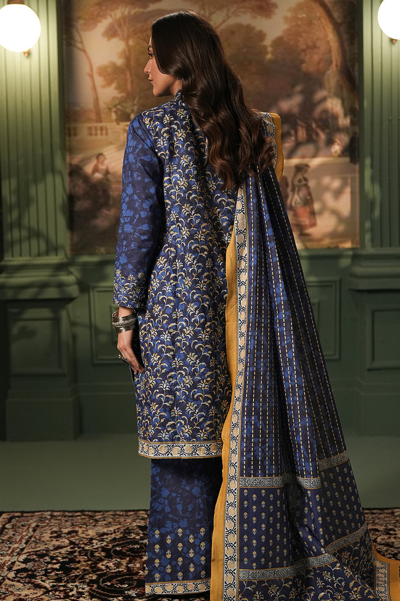 Woman wearing a blue embroidered traditional outfit with a matching dupatta in a decorative setting.