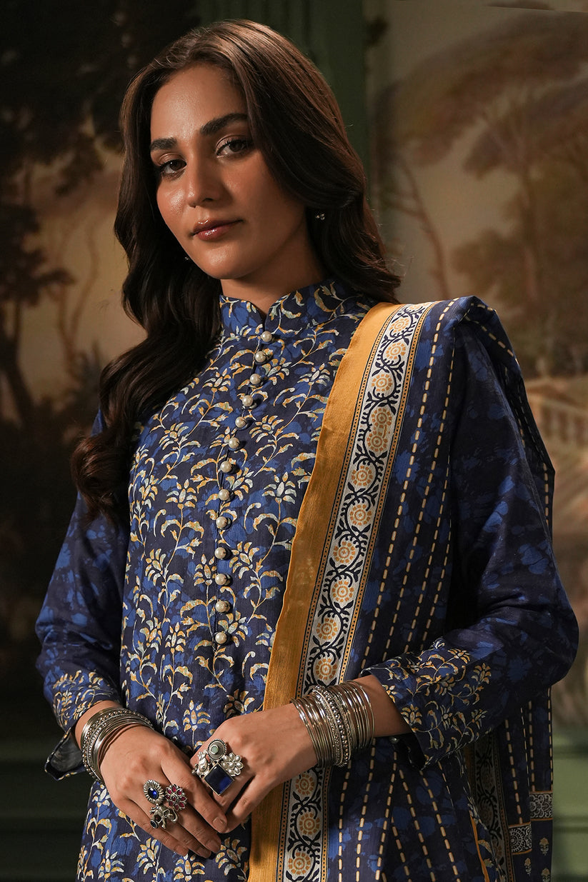 Woman in a blue traditional outfit with intricate patterns and gold accents.