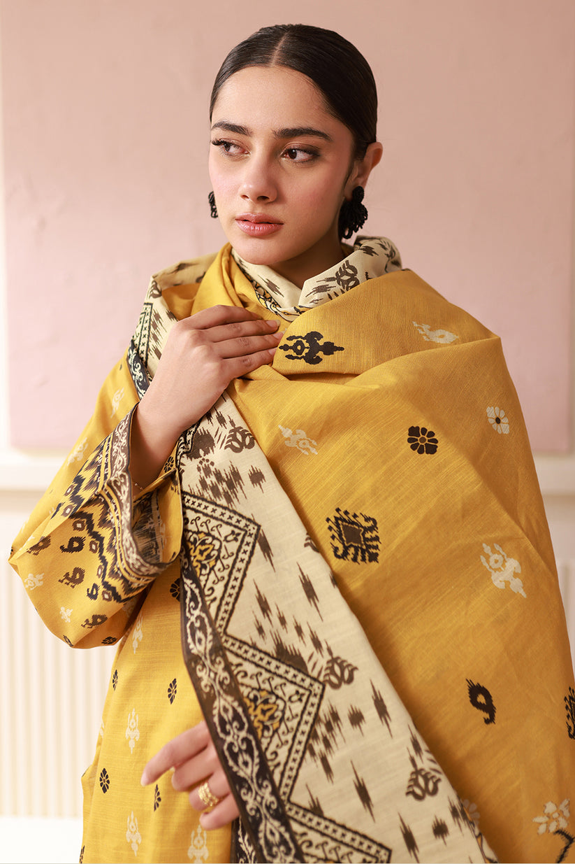 Woman wearing a yellow and beige traditional outfit with intricate patterns.
