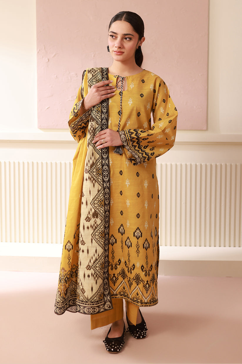 Woman wearing a yellow and black patterned outfit against a light pink wall.