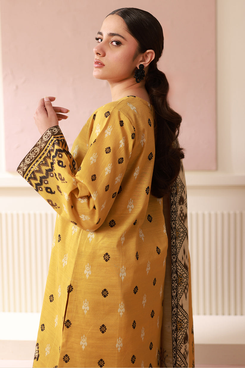Woman wearing a yellow kurta with black patterns in a neutral setting